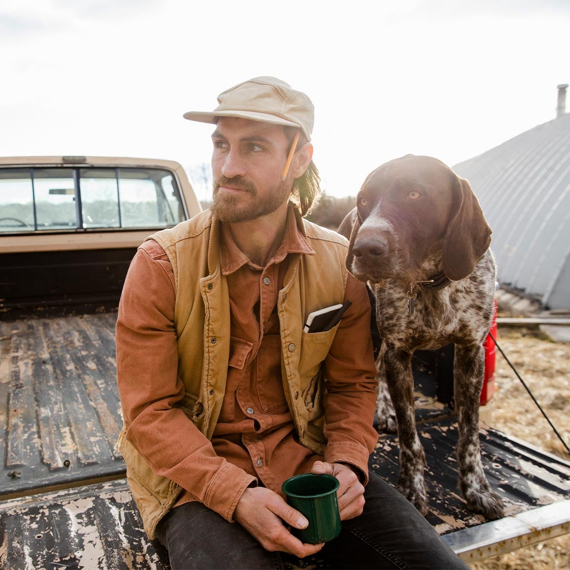 alberta farmer sitting with dog in back of pick up truck