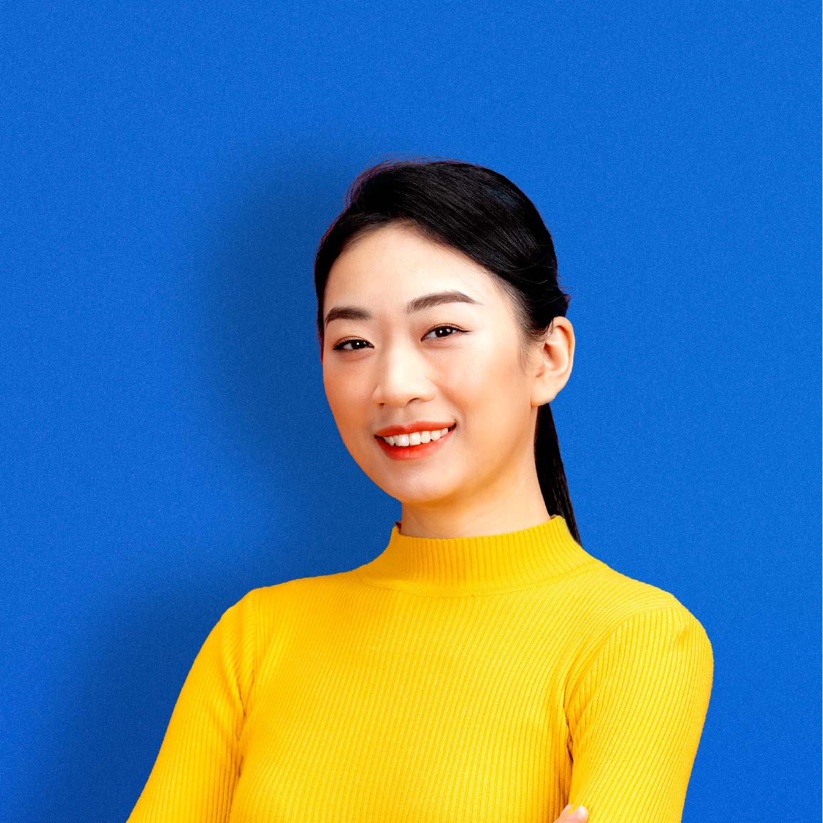 a girl in a yellow sweater smiling in front of a blue background
